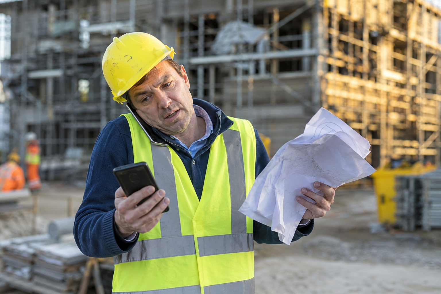 Werfleider die alles nog manueel beheert: twee telefoons en verfrommelde werfplannen